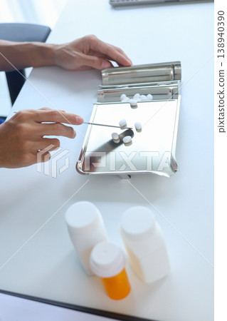 Pharmacist Counting White Medicine Pills on Stainless Steel Counting Tray in Pharmacy. Pharmacist Counting White Medicine Pills on Stainless Steel Counting Tray in Pharmacy. 138940390
