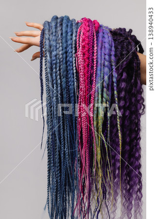 Female hand holding colorful braid extensions isolated on white background Female hand holding colorful braid extensions isolated on white background 138940433