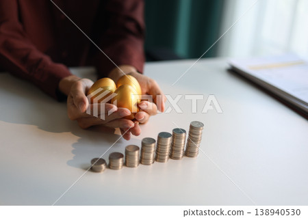 Rising stack of coins on the table and golden eggs on businessman hand metaphor for financial planning and investment return. Rising stack of coins on the table and golden eggs on businessman hand metaphor for financial planning and investment return. 138940530