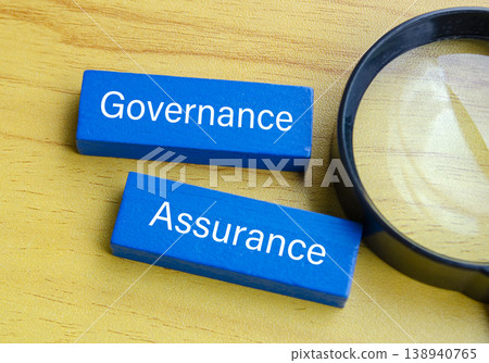 Blue governance assurance blocks with magnifying glass representing oversight concept. 138940765