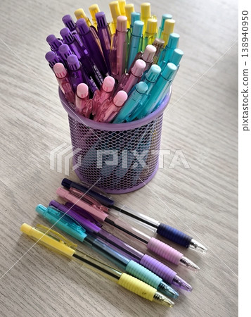 A multitude of bright, pastel pens on the table and in a glass. A multitude of bright, pastel pens on the table and in a glass. 138940950