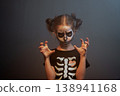 Girl with skull face paint making scary gesture in 138941168