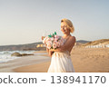 Blonde woman in summer dress holding bouquet and 138941170