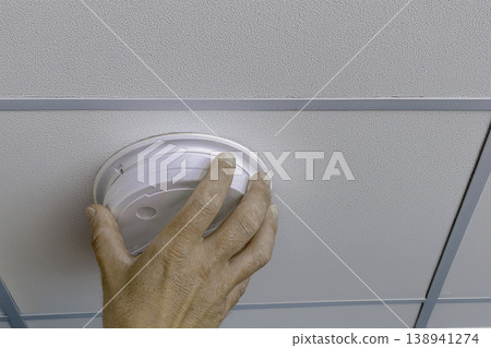 Installing smoke detector on ceiling panel 138941274