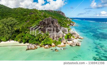 Granite rocks meeting turquoise water on a tropical coastline with lush greenery. Anse Source d'Argent. Seychelles, La Digue. Granite rocks meeting turquoise water on a tropical coastline with lush greenery. Anse Source d'Argent. Seychelles, La Digue. 138941398