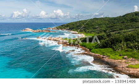 The turquoise ocean blending into the lush, green coastline with rocky formations. La Digue, Seychelles. The turquoise ocean blending into the lush, green coastline with rocky formations. La Digue, Seychelles. 138941406