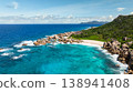Granite coastline with clear turquoise waters, white sandy beach, and vibrant greenery. Anse Marron beach. La Digue, Seychelles. 138941408