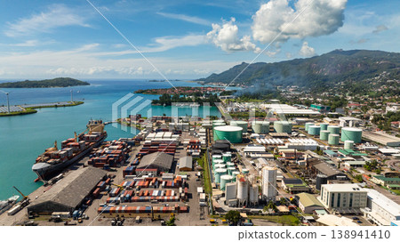 Large shipping containers and storage tanks located by the harbor, with green islands and turquoise waters in the background. Victoria. Seychelles, Mahe. 138941410