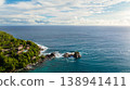 A dense green forest covering a rocky coastline, with clear turquoise waters. Seychelles, Mahe. 138941411