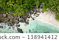Clear emerald waters gently lapping against a sandy beach surrounded by lush greenery. Butzel Beach. Seychelles, Mahe. 138941412