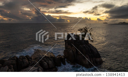 Solitary rock with palm trees amidst ocean waves at sunset. Seychelles, Mahe. Solitary rock with palm trees amidst ocean waves at sunset. Seychelles, Mahe. 138941413