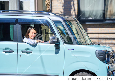 一位日本女子坐在汽車駕駛座上,望著窗外,帶著微笑。 一位日本女子坐在汽車駕駛座上,望著窗外,帶著微笑。 138942163