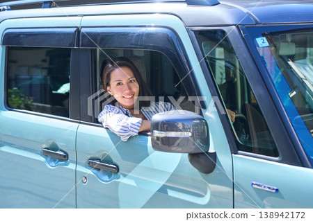 一位日本女子坐在汽車駕駛座上，望著窗外，帶著微笑。 138942172
