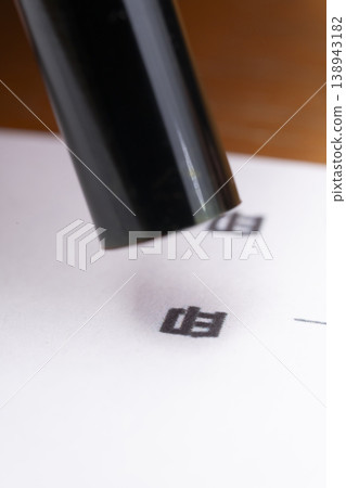一隻手正在往印章上塗抹紅墨。 一隻手正在往印章上塗抹紅墨。 138943182