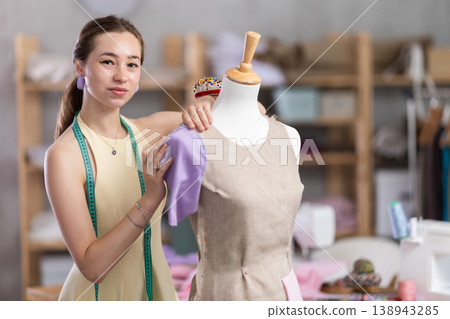 Woman seamstress adjusts clothes on mannequin Woman seamstress adjusts clothes on mannequin 138943285
