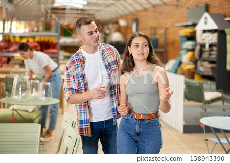 Spouses look for something in furniture store, searching for perfect item to complete patio Spouses look for something in furniture store, searching for perfect item to complete patio 138943390