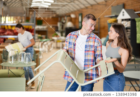 Cheerful couple evaluating patio chairs options in garden store Cheerful couple evaluating patio chairs options in garden store 138943398