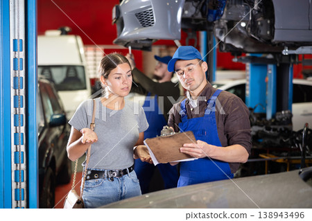 Mechanic guy signs agreement with young woman client Mechanic guy signs agreement with young woman client 138943496