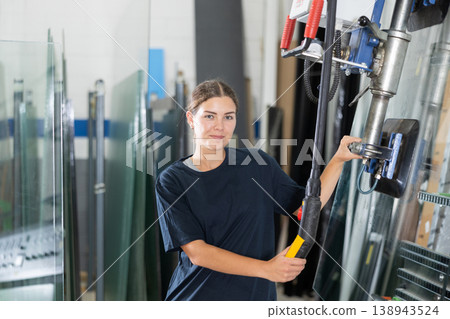 Female employee operating industrial glass lifter in production workshop 138943524
