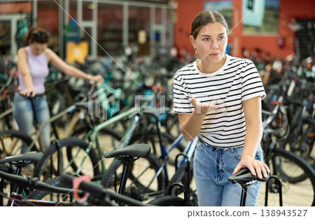Girl assessing saddle while choosing bicycle in store 138943527