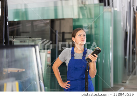 Female worker using remote control to operate machinery in glass workshop 138943539