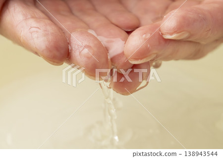Scoop up the water from the washbasin with both hands. Scoop up the water from the washbasin with both hands. 138943544