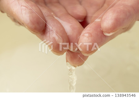 用雙手從洗臉盆裡舀水。 138943546