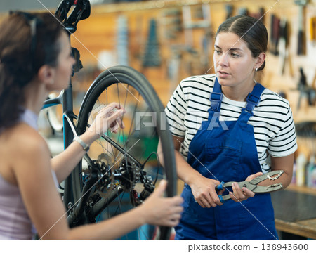 Female bicycle repair service worker consults client 138943600