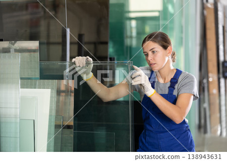 Female employee inspecting glass sheets in production workshop Female employee inspecting glass sheets in production workshop 138943631