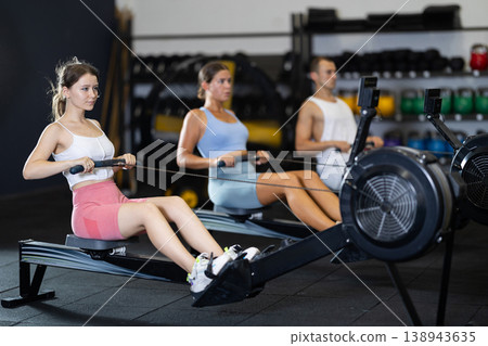 Young woman exercising on rowing machine Young woman exercising on rowing machine 138943635