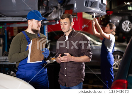 Mechanic guy signs agreement with young man client Mechanic guy signs agreement with young man client 138943673