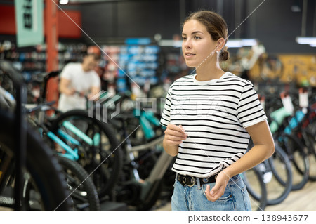Young woman standing in bicycle shop and choosing new sport bike 138943677