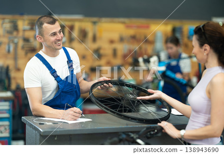 Bike mechanic discussing repair details with female customer Bike mechanic discussing repair details with female customer 138943690