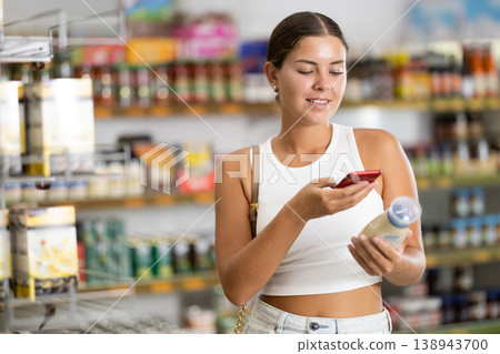 Girl scanning barcode or qr code with smartphone on mayonnaise label in supermarket Girl scanning barcode or qr code with smartphone on mayonnaise label in supermarket 138943700