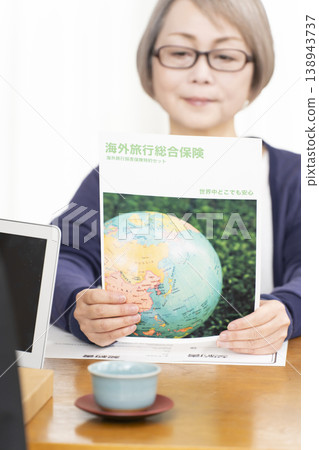 A senior woman's hands as she signs and stamps her overseas travel insurance contract. 138943737