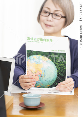 一位老婦人正在簽署並蓋章她的海外旅行保險合約。 一位老婦人正在簽署並蓋章她的海外旅行保險合約。 138943738