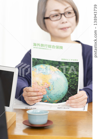 一位老婦人正在簽署並蓋章她的海外旅行保險合約。 一位老婦人正在簽署並蓋章她的海外旅行保險合約。 138943739