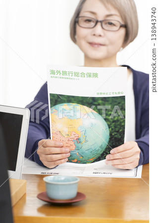 一位老婦人正在簽署並蓋章她的海外旅行保險合約。 138943740
