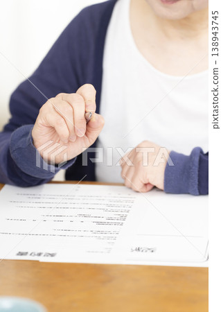 一位老婦人正在簽署並蓋章她的海外旅行保險合約。 一位老婦人正在簽署並蓋章她的海外旅行保險合約。 138943745