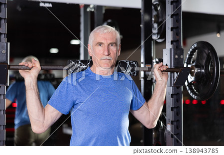Active man during exercises to strengthen muscles of hands and body using barbell and extra weight Active man during exercises to strengthen muscles of hands and body using barbell and extra weight 138943785