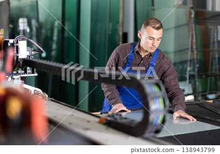 Factory technician processing glass sheet on cutting machine Factory technician processing glass sheet on cutting machine 138943799