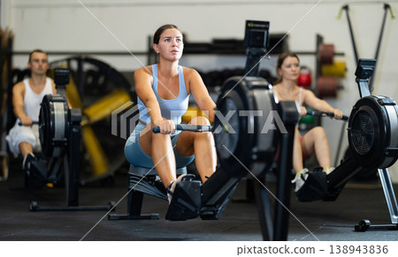 Young woman exercising on rowing machine 138943836