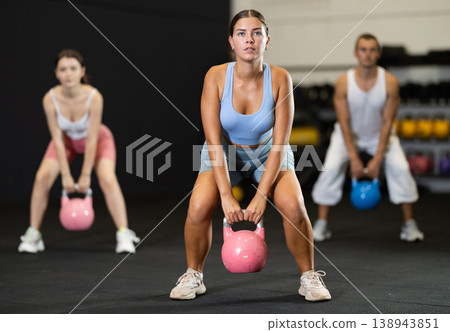 Sporty athletic woman in sportswear training with kettlebell in sport gym Sporty athletic woman in sportswear training with kettlebell in sport gym 138943851