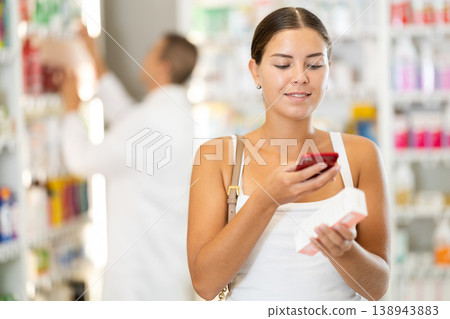 In pharmacy girl customer scans QR code on label box, photographs packaging. In pharmacy girl customer scans QR code on label box, photographs packaging. 138943883