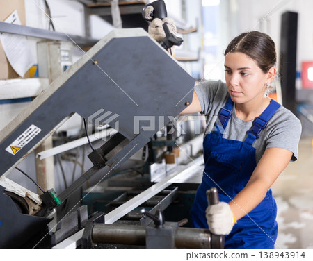 Female technician operating profile cutting machine in production workshop Female technician operating profile cutting machine in production workshop 138943914