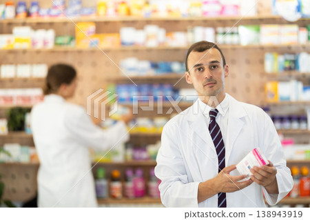 Young male pharmacist offering preparation in box Young male pharmacist offering preparation in box 138943919