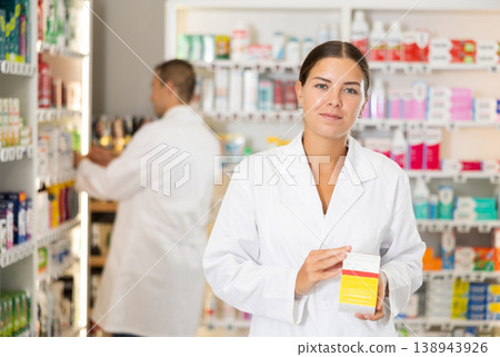 Female consultant pharmacist holds box in hands and offers to purchase remedy to alleviate condition Female consultant pharmacist holds box in hands and offers to purchase remedy to alleviate condition 138943926