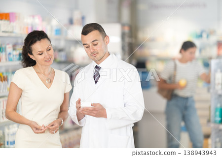Man pharmacist helps woman buyer to decide on choice an medicine Man pharmacist helps woman buyer to decide on choice an medicine 138943943