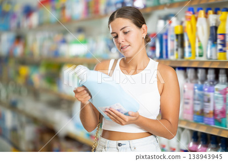 Girl customer in store chooses package of laundry detergent Girl customer in store chooses package of laundry detergent 138943945