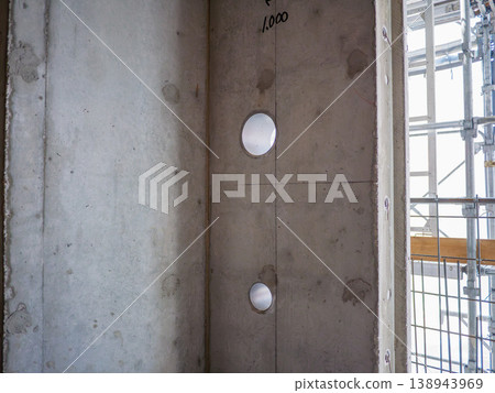 Concrete wall with pipe sleeve holes and markings at an RC (reinforced concrete) construction site. 138943969